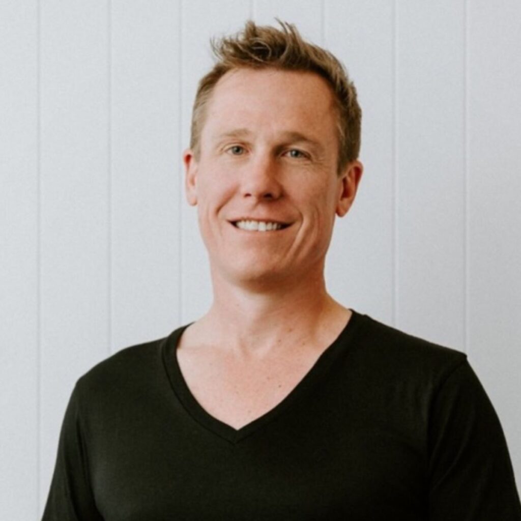 Photo of Ash Crick in a black shirt on a white background.